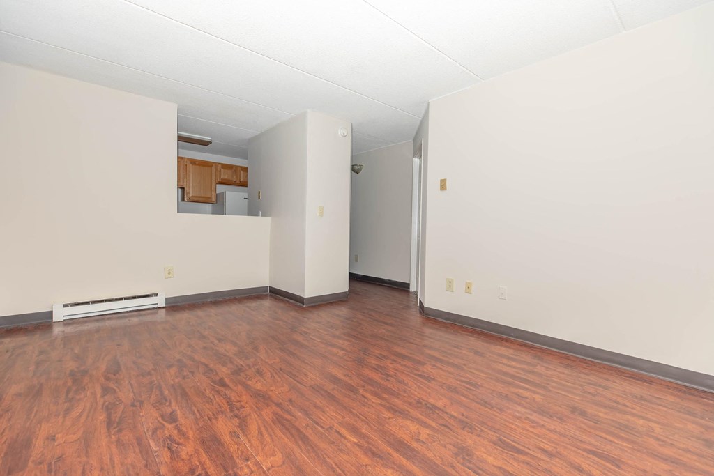 an empty living room with wood floors and white walls