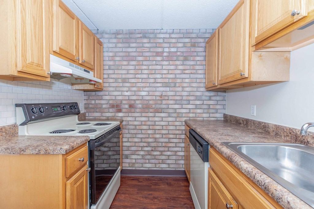 a kitchen with wooden cabinets and a brick wall