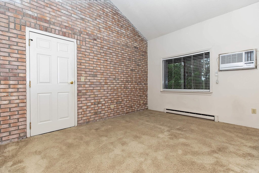 an empty room with a brick wall and a white door
