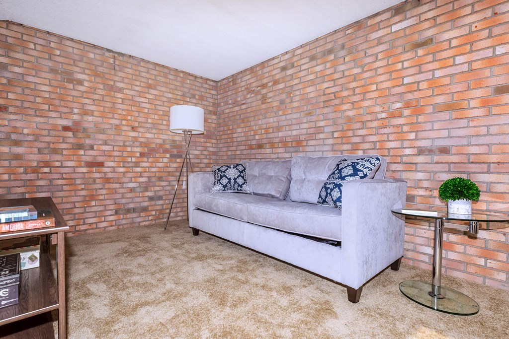 a living room with a couch and a brick wall