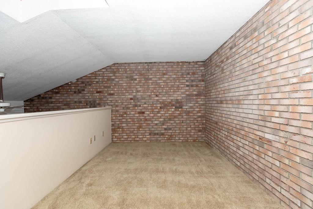 a room with a brick wall and a carpeted floor