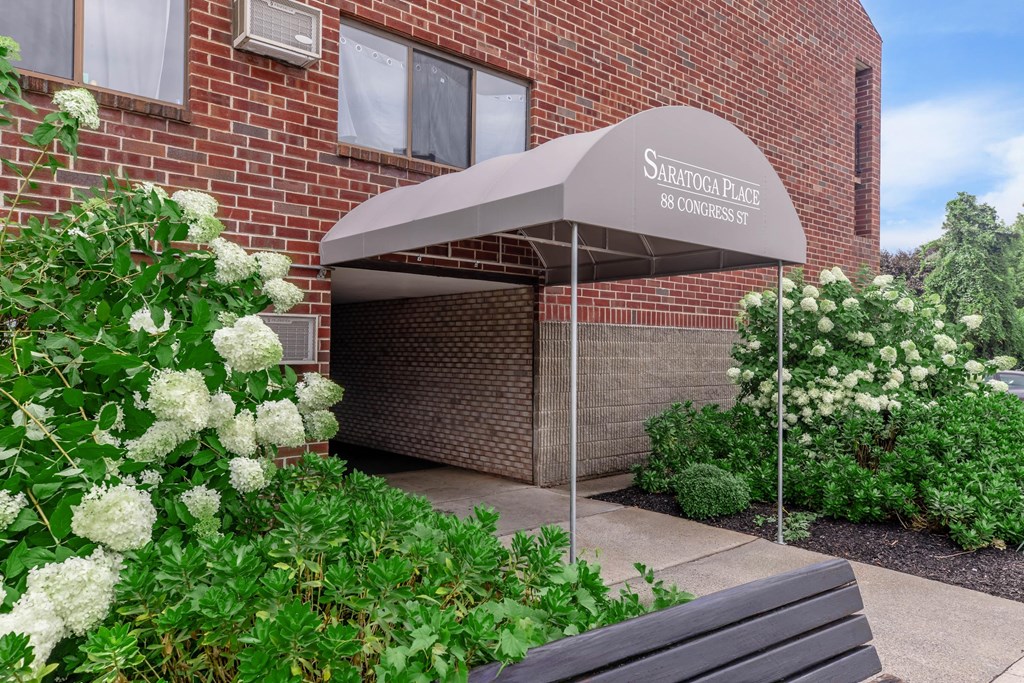 the front of a brick building with a canopy and a bench