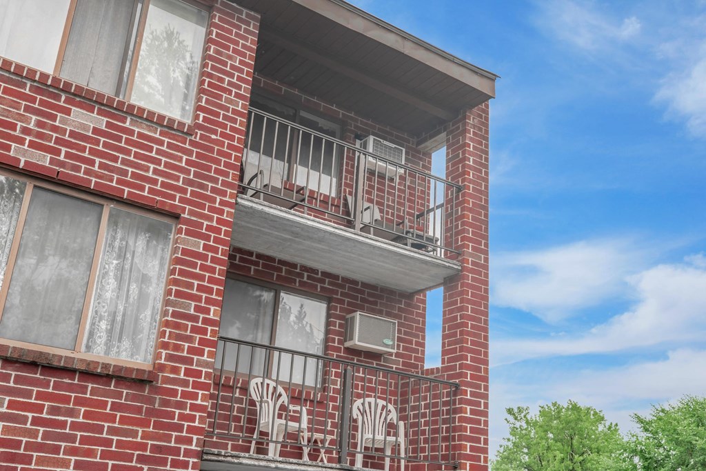 a brick apartment building with a balcony and a blue sky
