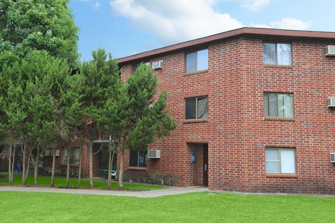 a red brick building with green grass and trees