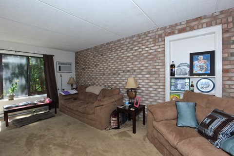 a living room with two couches and a brick wall