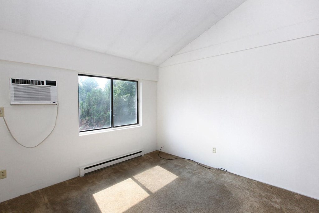 an empty room with a window and a air conditioner