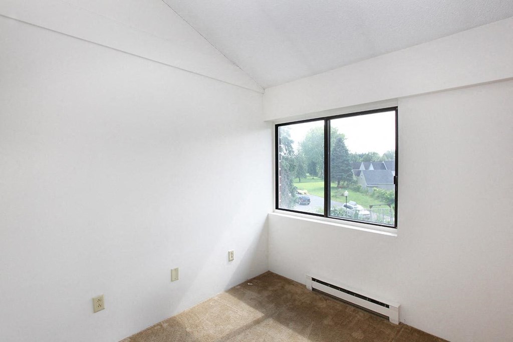 an empty room with a large window and white walls