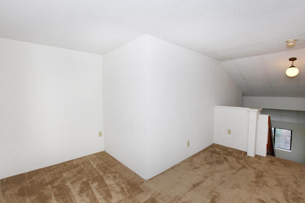 an empty living room with white walls and carpet