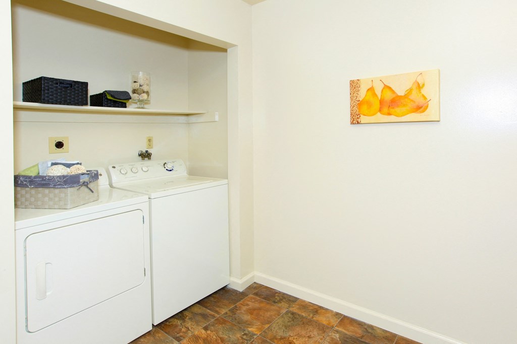 a washer and dryer in a laundry room with a sink and a painting