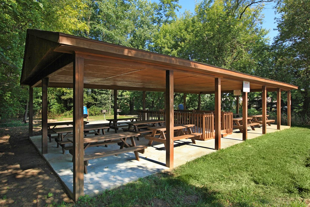 a covered picnic area with benches in a park