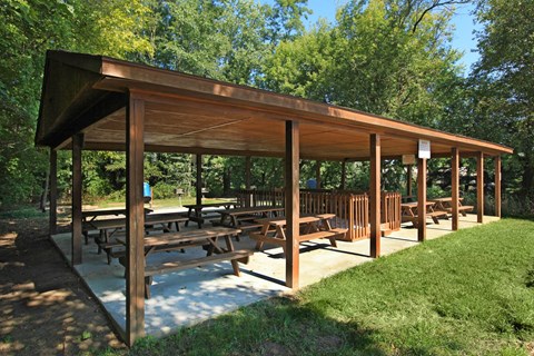 a covered picnic area with benches in a park