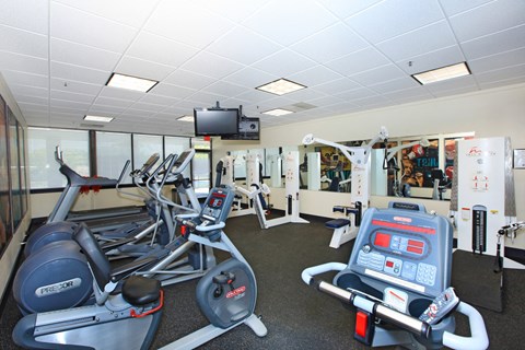 a gym with various exercise equipment and a tv