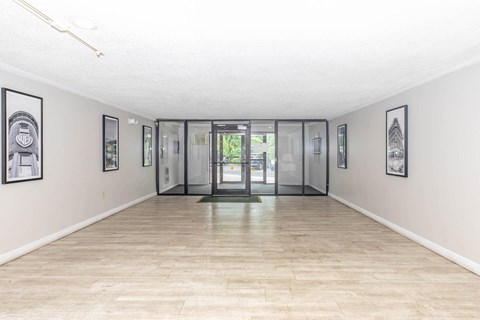 a large room with a glass door and paintings on the walls
