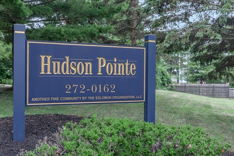 a blue sign that reads hudson point in front of a lawn and trees