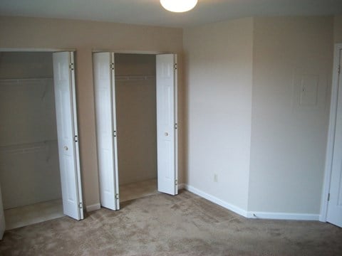 a bedroom with three closets and a carpeted floor