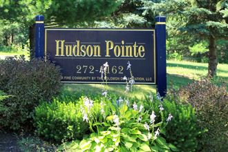 a sign for hudson point in front of a garden