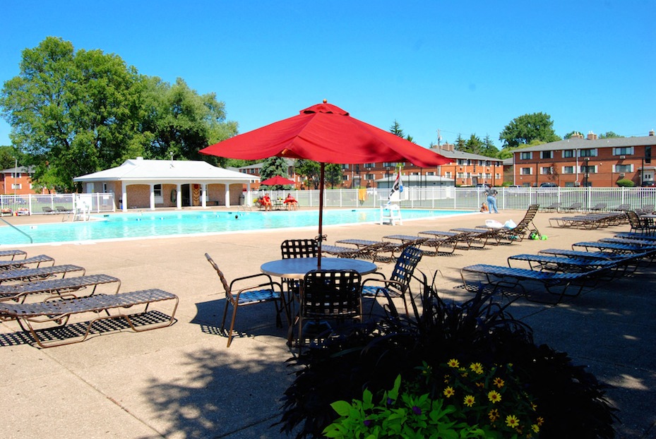 a pool with tables and chairs and a red umbrella