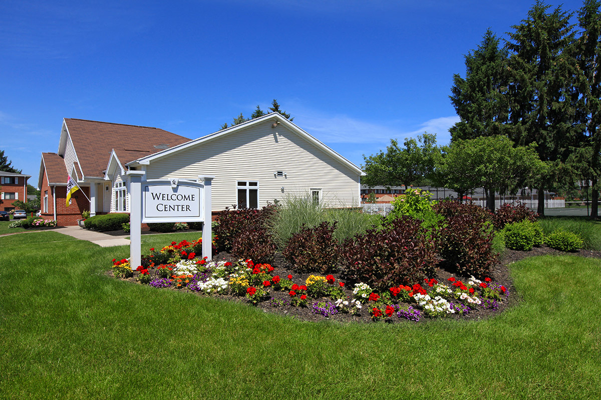 the welcome sign and flowers in front of a white building