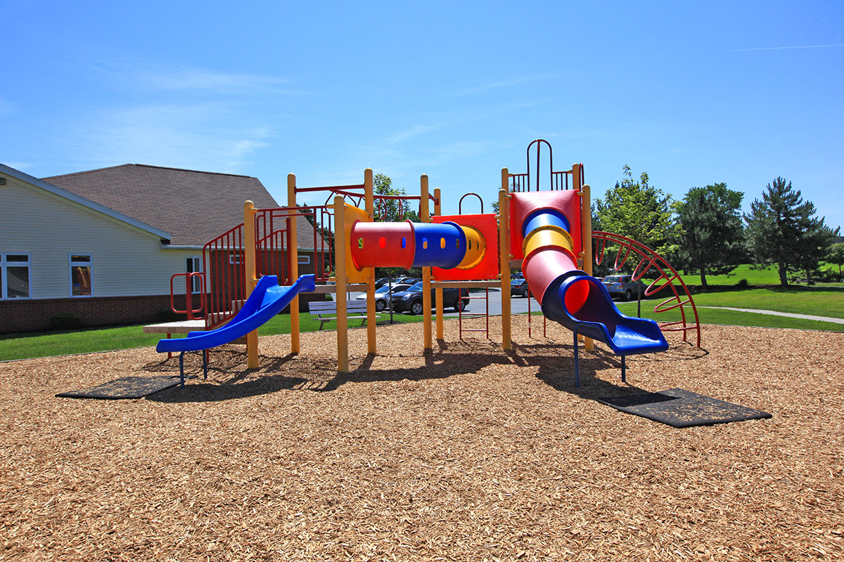 a playground with slides and a building in the background