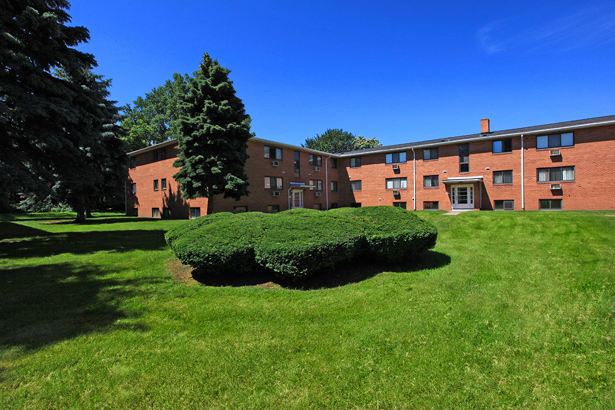 the front of a brick building with grass and trees