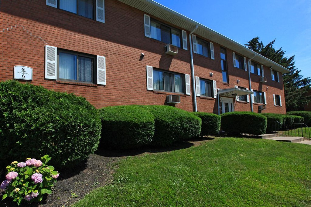 a brick apartment building with a yard and bushes