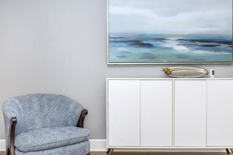 a blue chair in a room with a painting on the wall