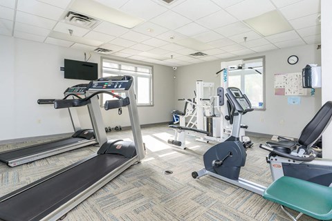 a gym with cardio machines and a tv
