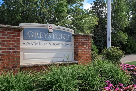 a sign and townhomes in front of a brick wall
