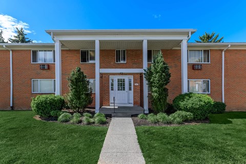 the front of a red brick house with a white front door