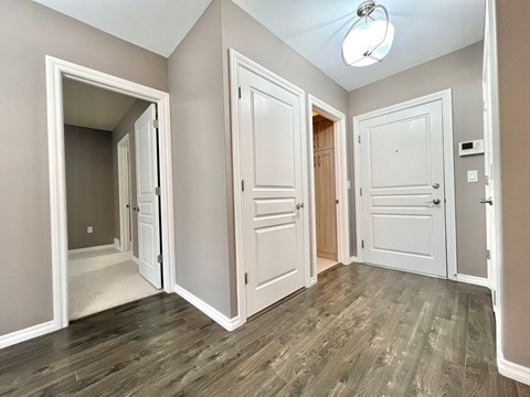 an empty living room with white doors and wood flooring