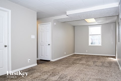 the living room of an apartment with carpet and a white door