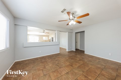 an empty living room with a ceiling fan and tile flooring