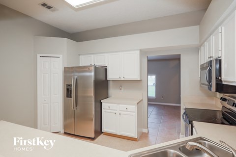 a kitchen with white cabinets and a stainless steel refrigerator