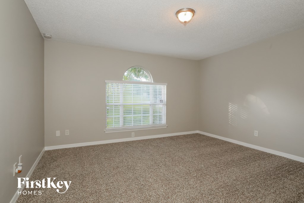 a bedroom with carpet and a large window