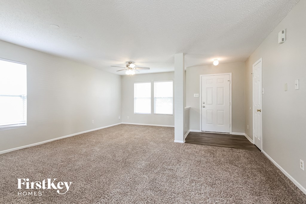 a spacious living room with carpet and a ceiling fan