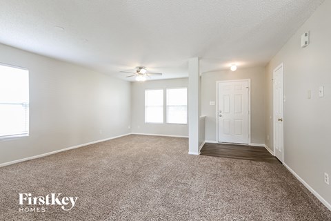 a spacious living room with carpet and a ceiling fan