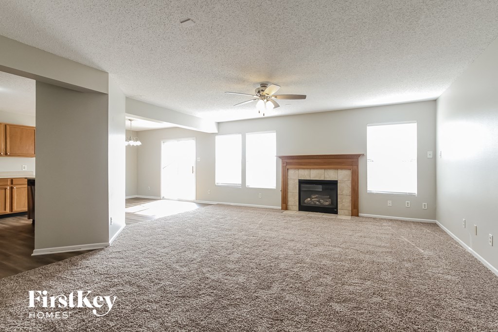 an empty living room with a fireplace and a ceiling fan