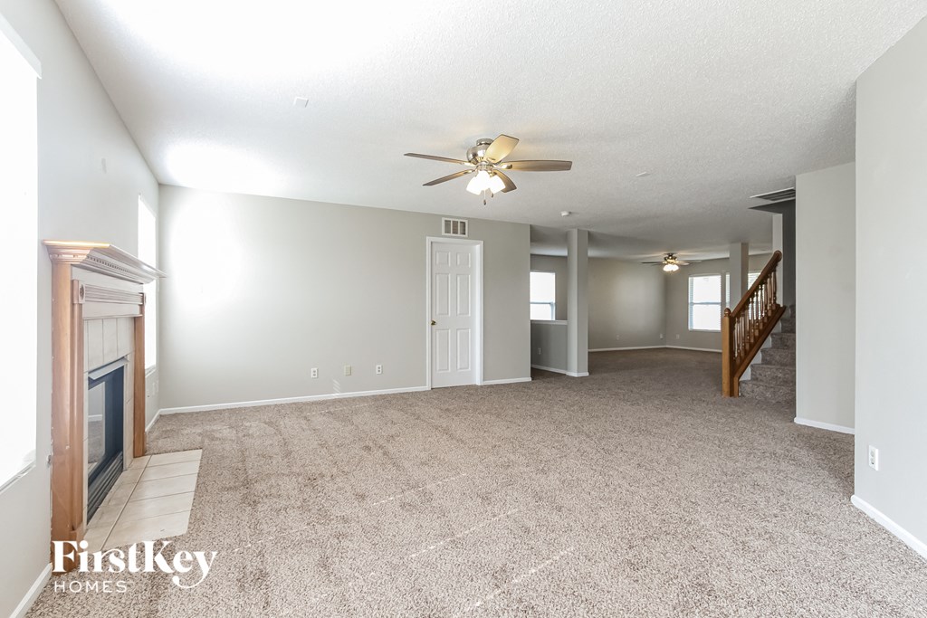 an empty living room with a fireplace and a ceiling fan