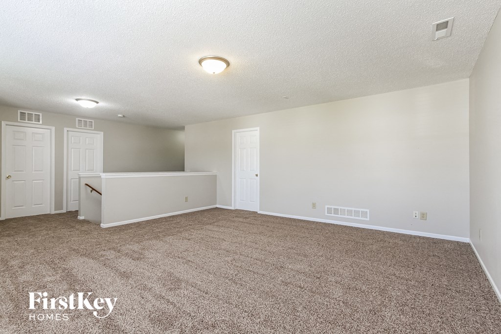 a spacious living room with carpet and white doors