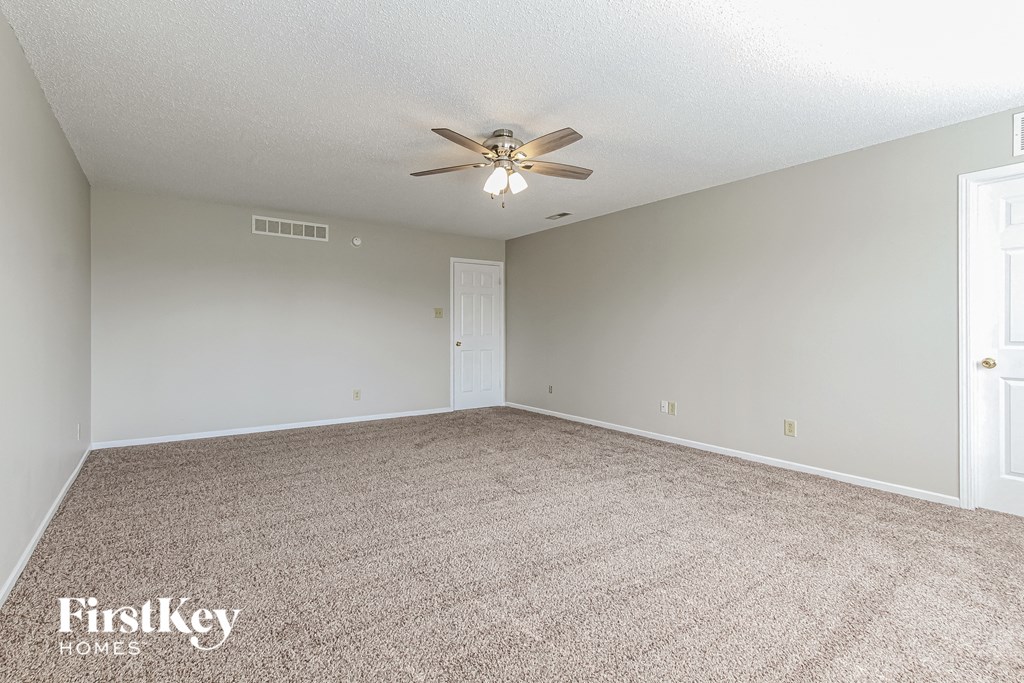 a spacious living room with carpet and a ceiling fan