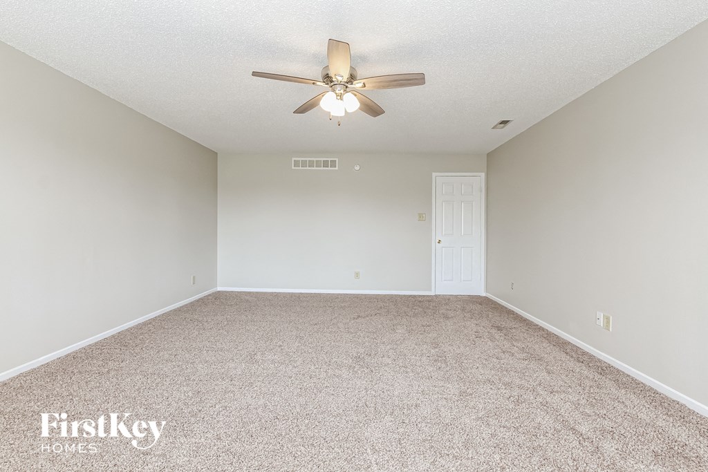 a spacious living room with carpet and a ceiling fan