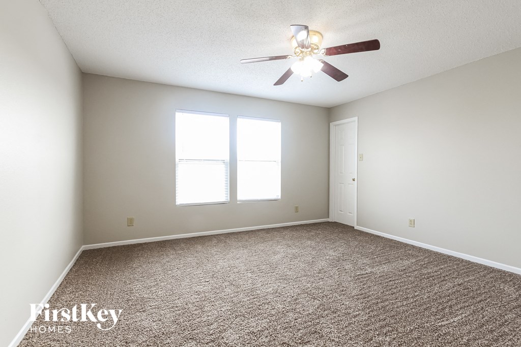 an empty room with a ceiling fan and two windows