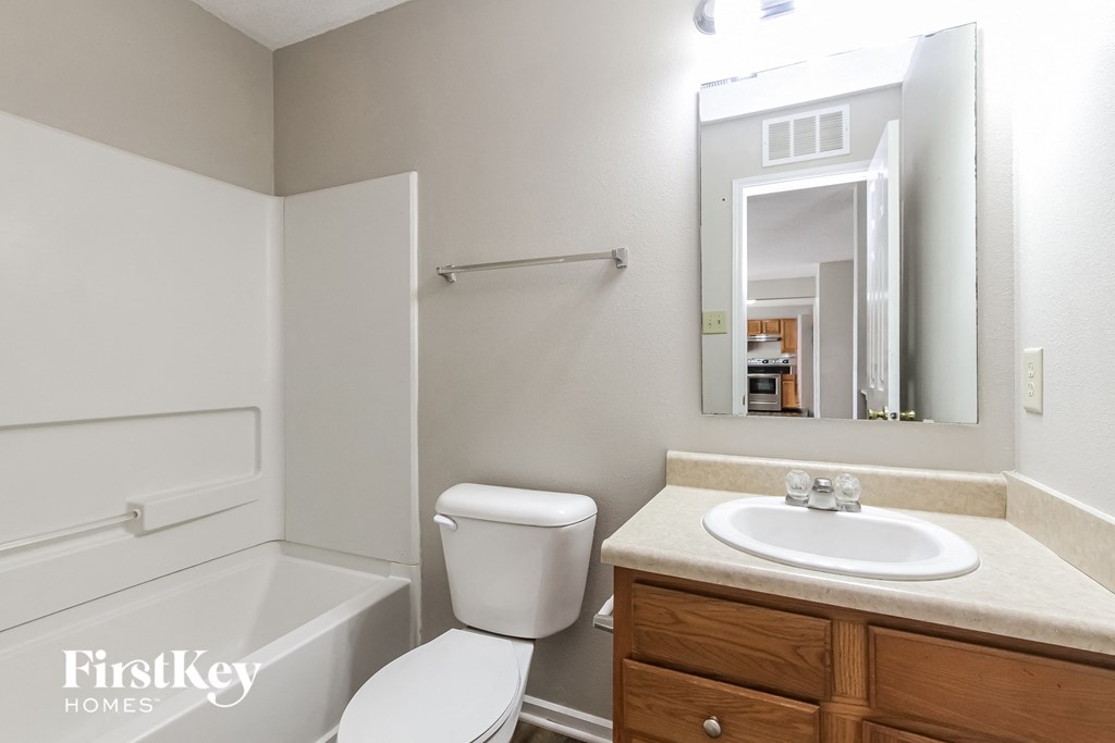 a bathroom with a toilet sink and tub and a mirror