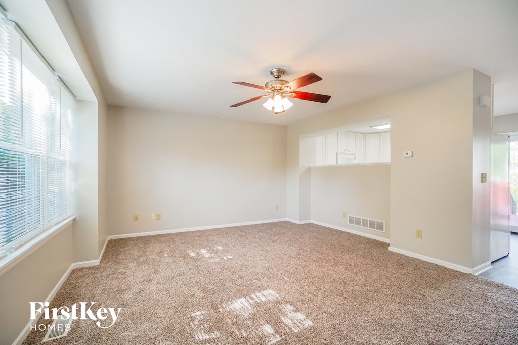 A spacious room with a ceiling fan and carpeted floor.