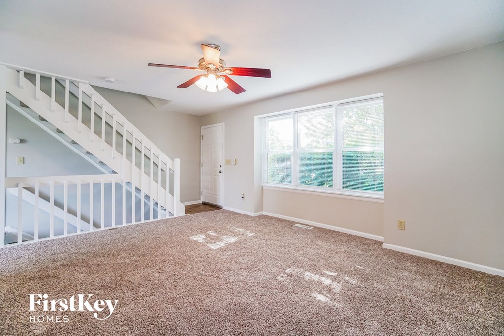 A spacious room with a carpeted floor and a ceiling fan.
