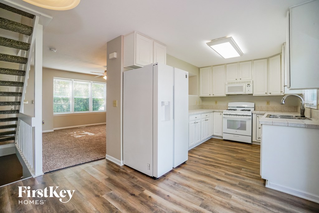 A kitchen with a refrigerator, oven, and microwave.