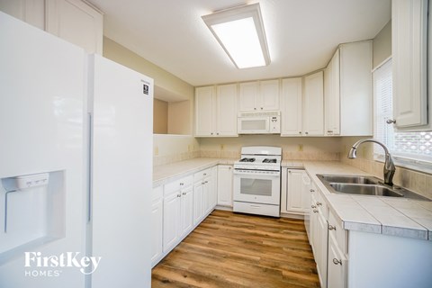 A kitchen with white cabinets and a white fridge.