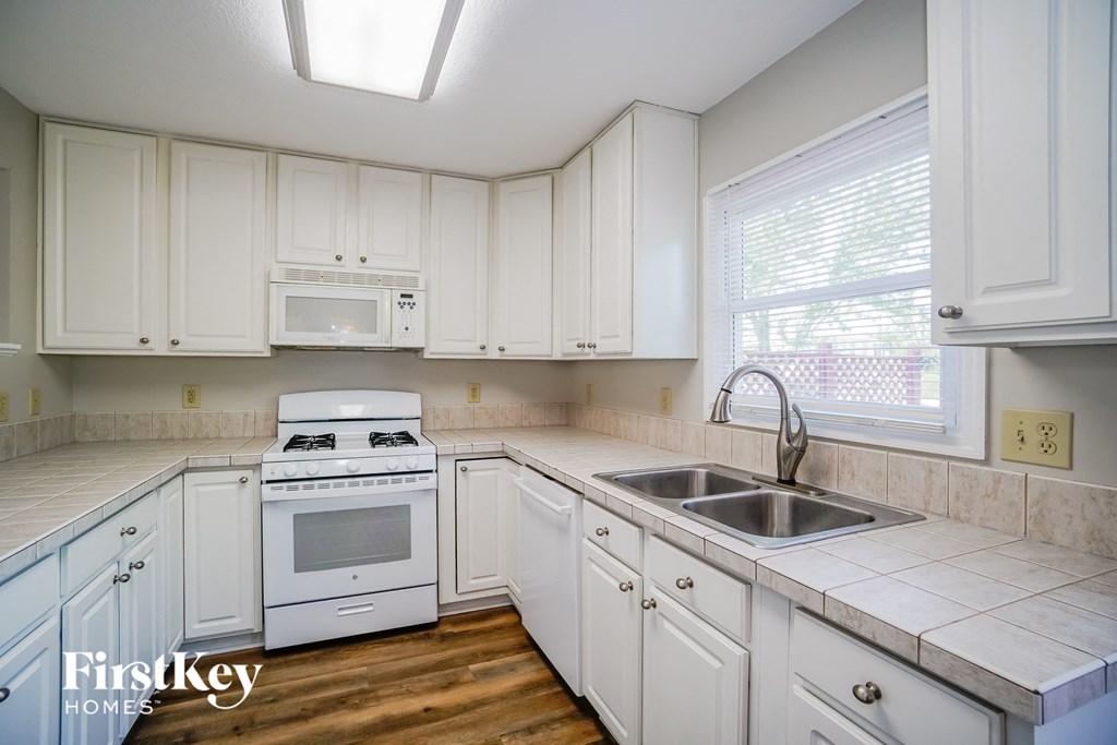 A kitchen with white cabinets and a stove top oven.