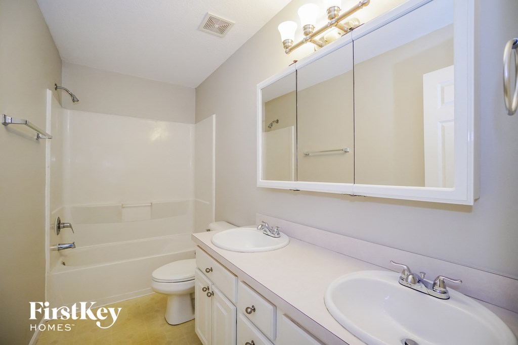 A white bathroom with a toilet, sink, and mirror.