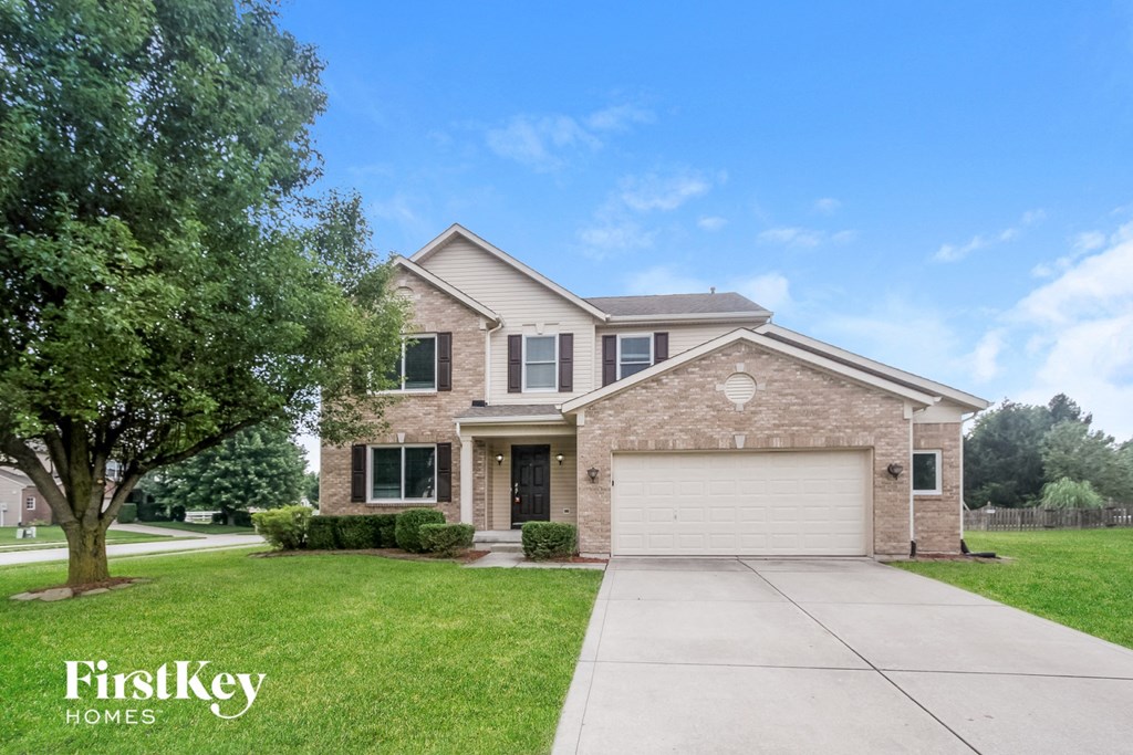 a brick house with a white garage door and a lawn